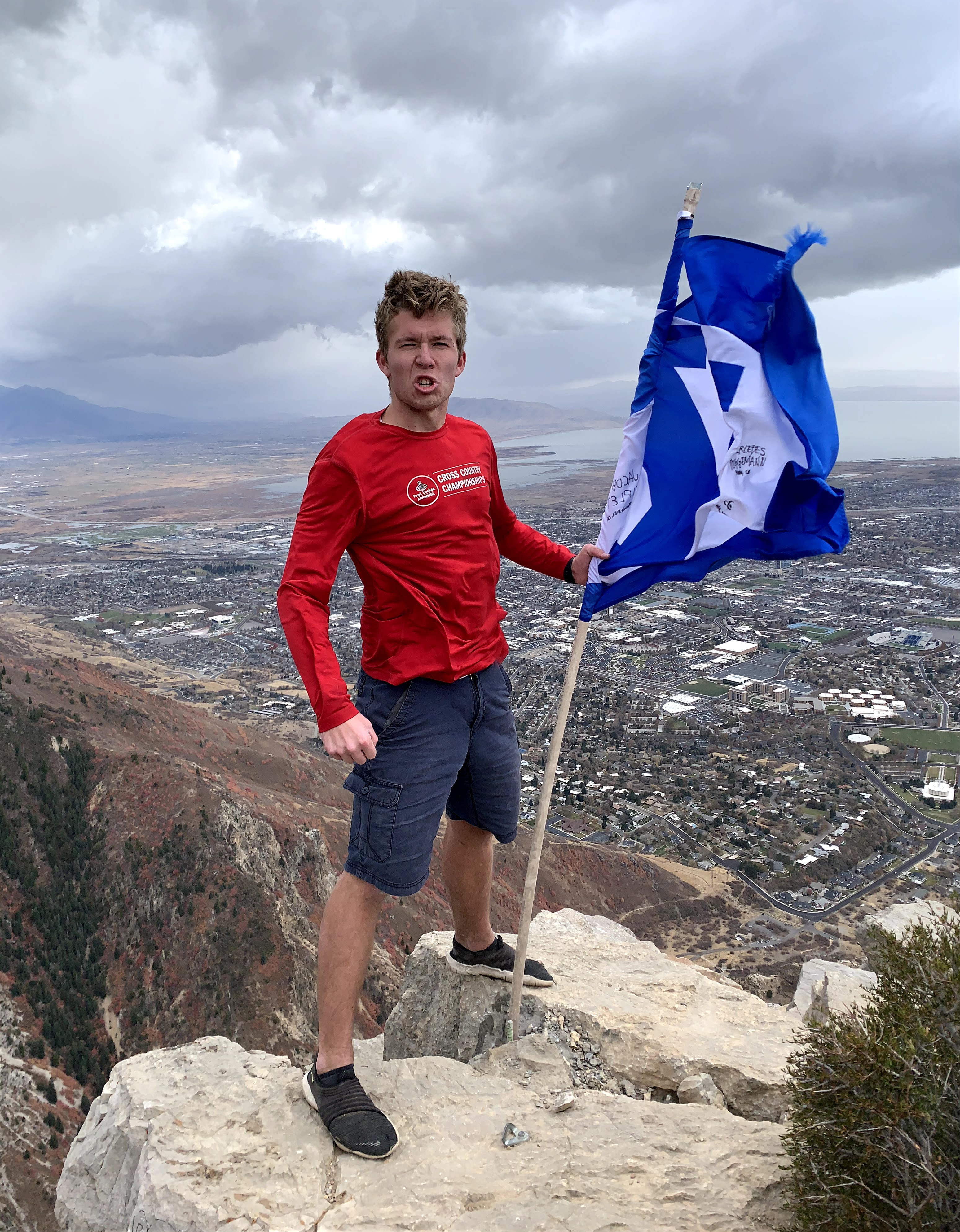 Kamryn is on the top of Squaw Peak holding the BYU flag